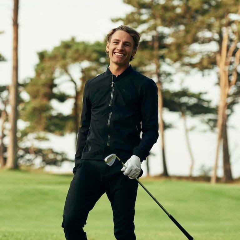 Lachende golfer met golfclub op de green bij Golf Waterland Academy in Amsterdam.